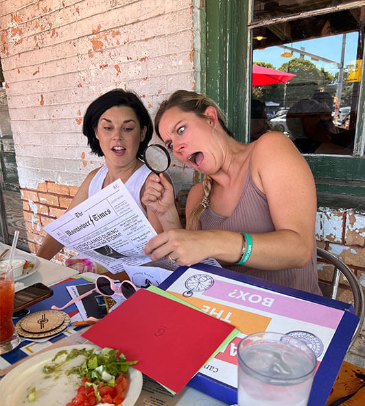 shocked woman and her friend taking a picture with a newspaper